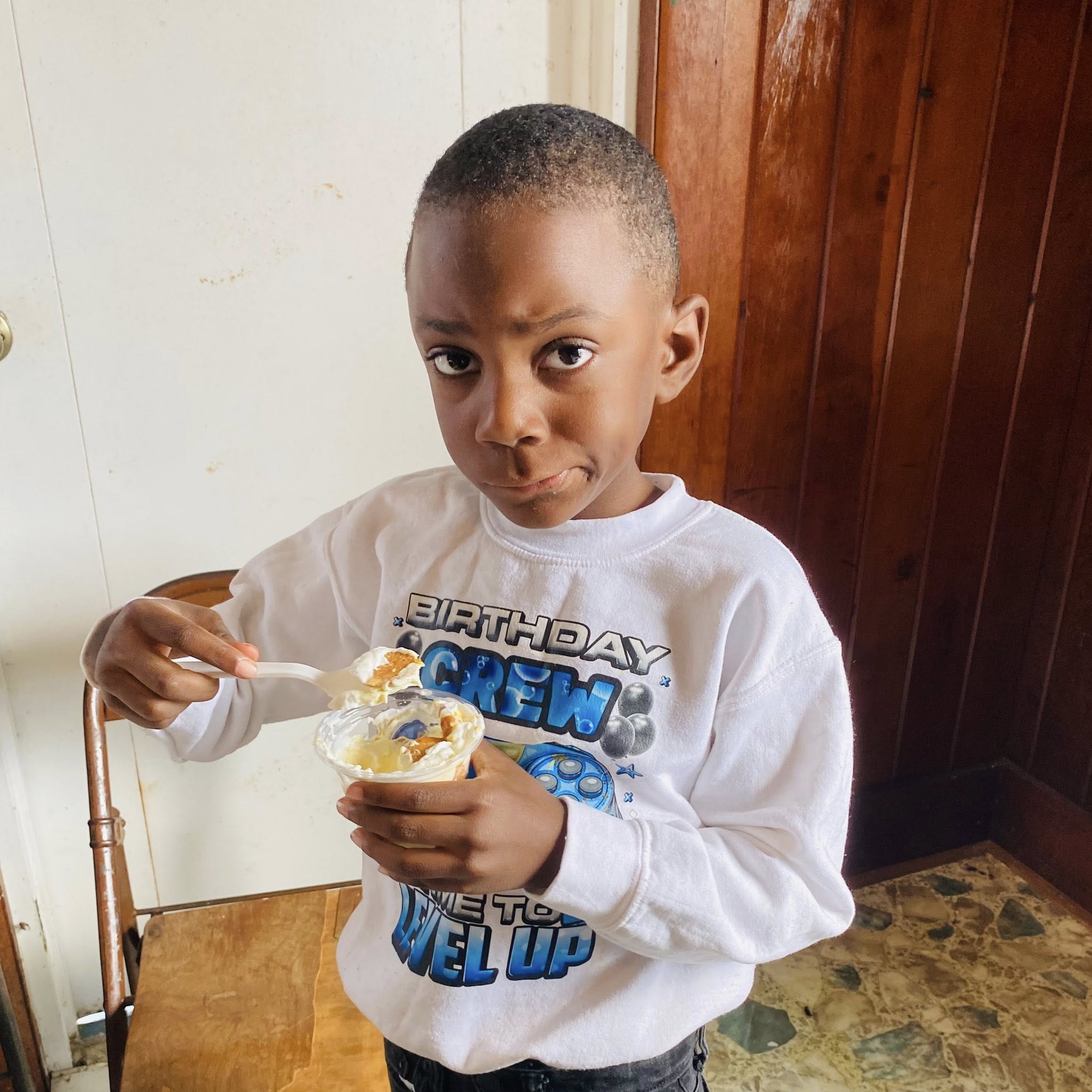 A little boy eating something out of a cup.